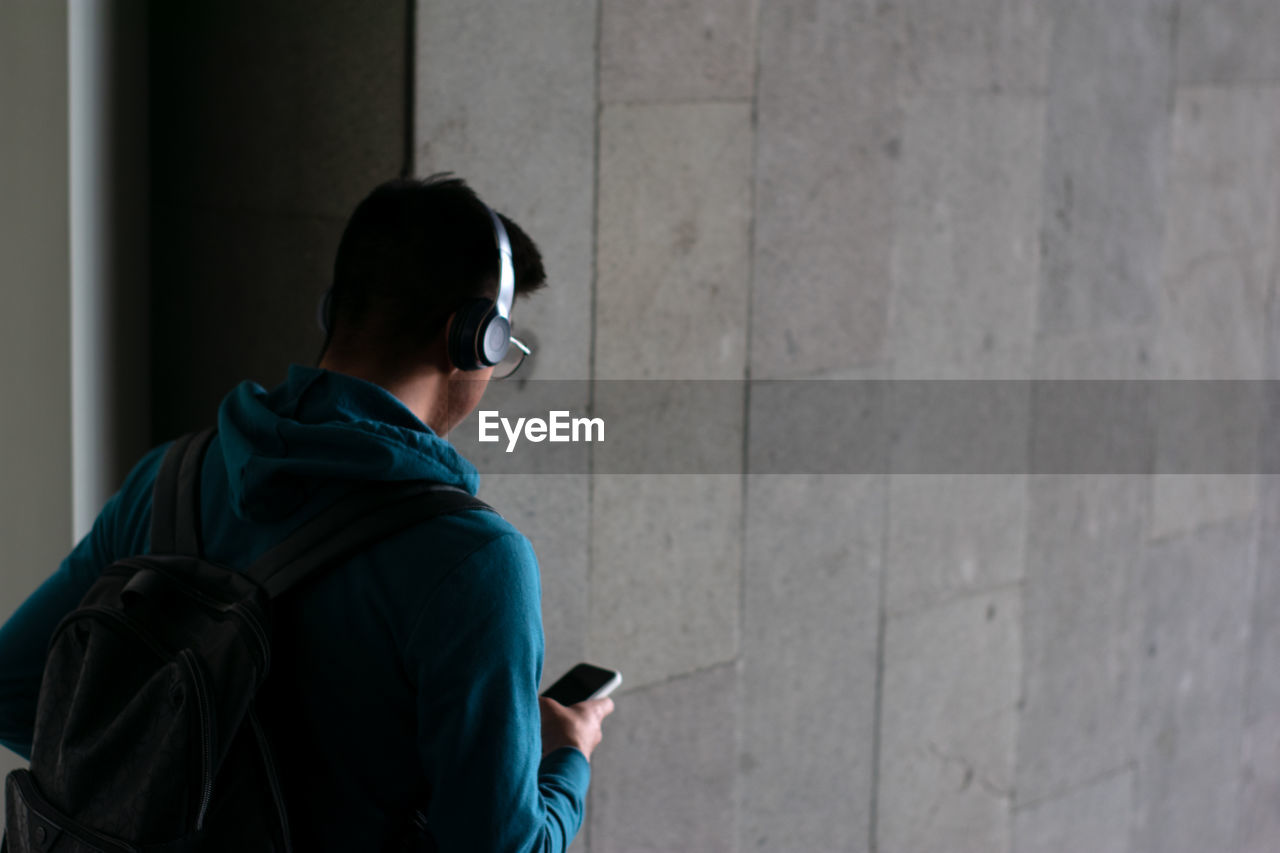 Unrecognizable person goes down stairs with his smartphone on the hand and copy space