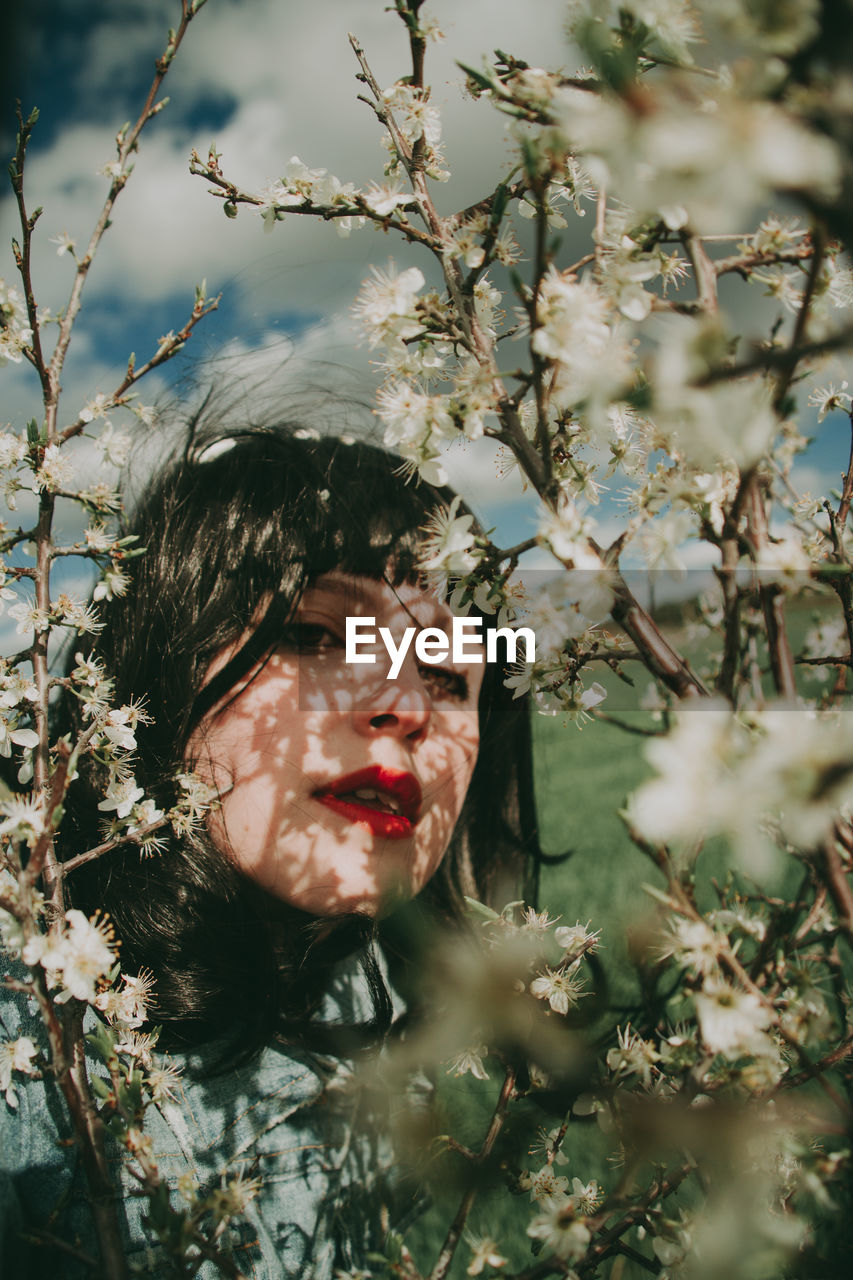 Portrait of woman with pink flowers on tree