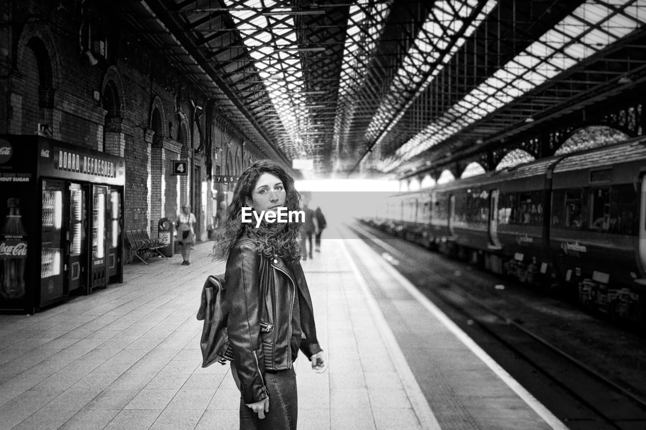 Side view portrait of woman standing at railroad station
