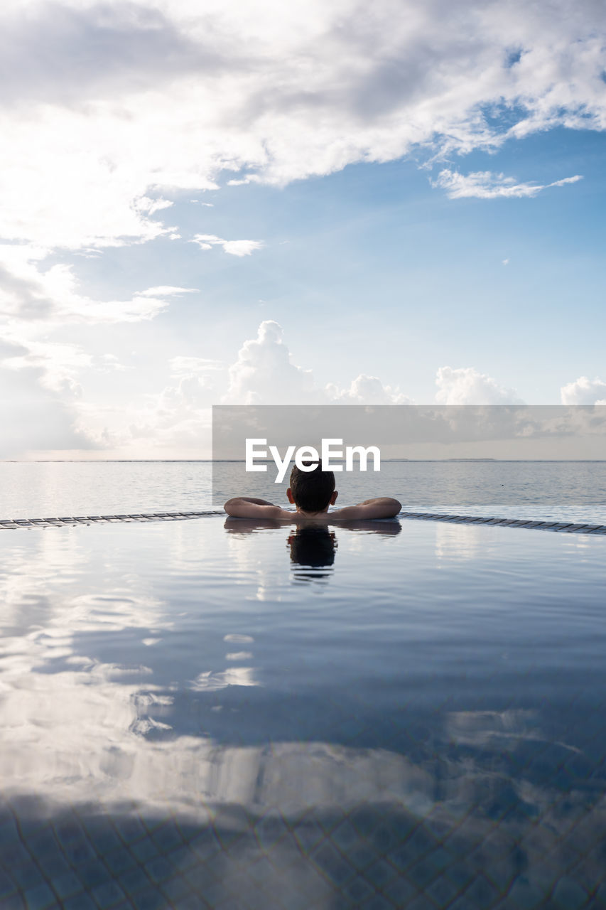 Little kid looking the ocean from a infinity pool