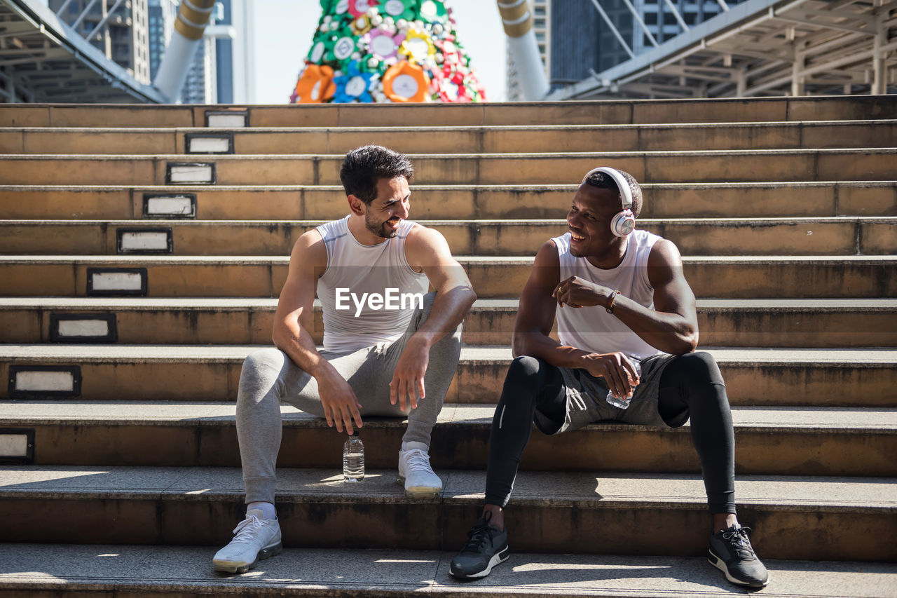 Full length of male friends sitting on steps