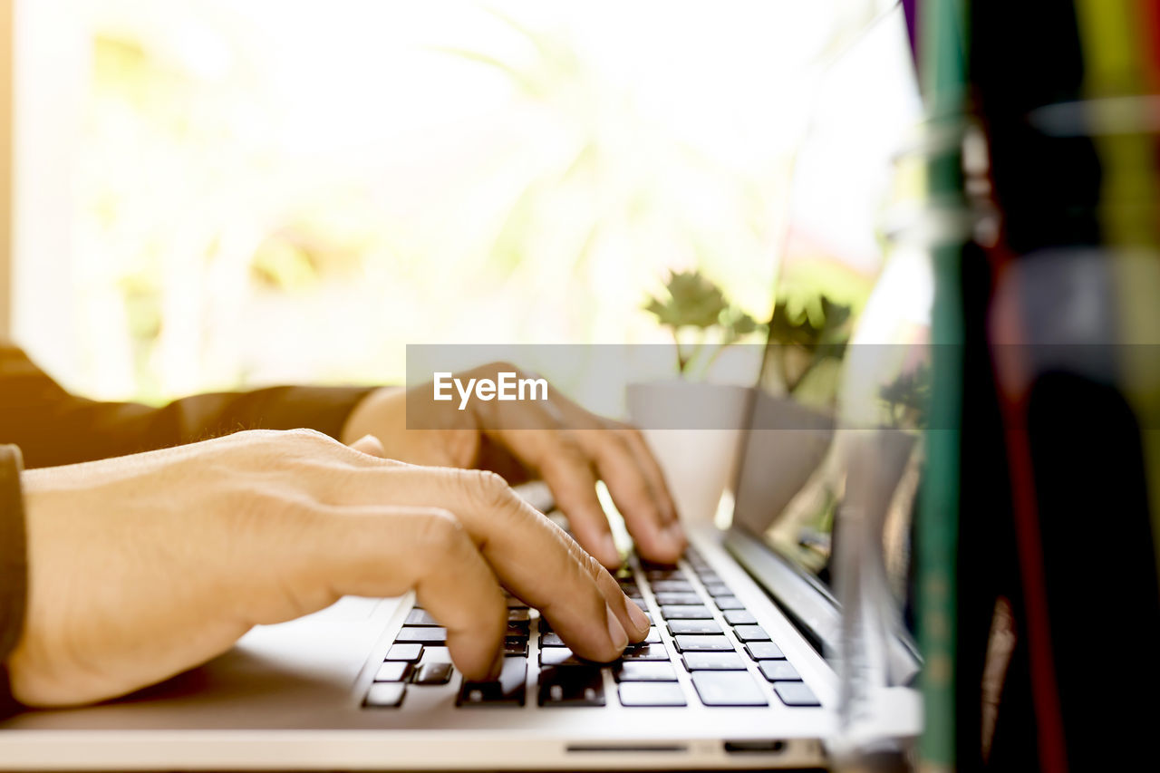 Close-up of cropped hands using laptop