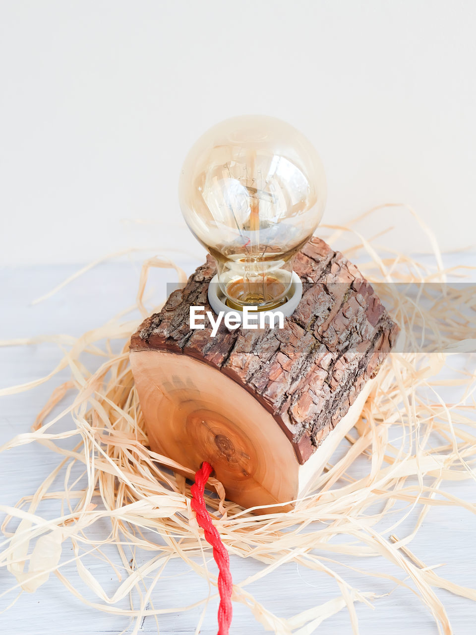 Close-up of light bulb on wood against white background