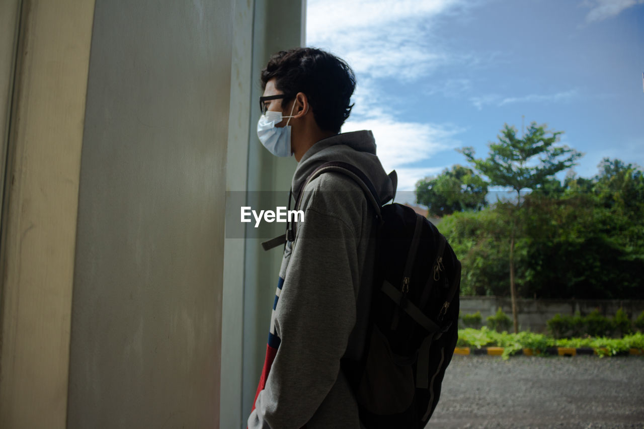 Side view of young man looking outside