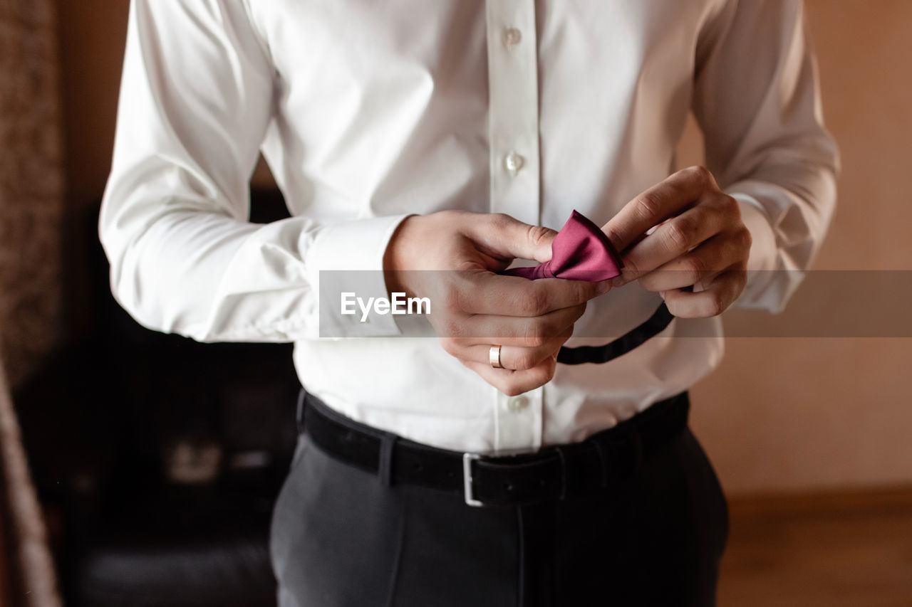 midsection of businessman holding mobile phone