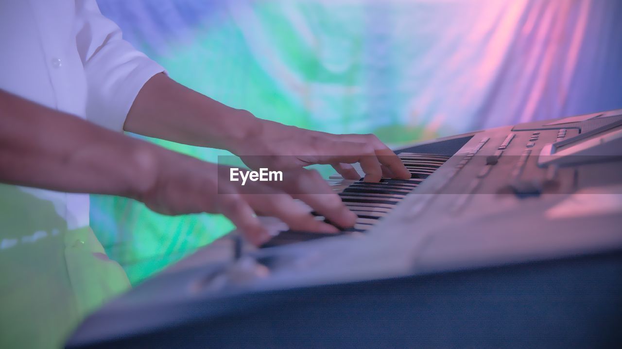 MIDSECTION OF MAN PLAYING PIANO IN NIGHTCLUB