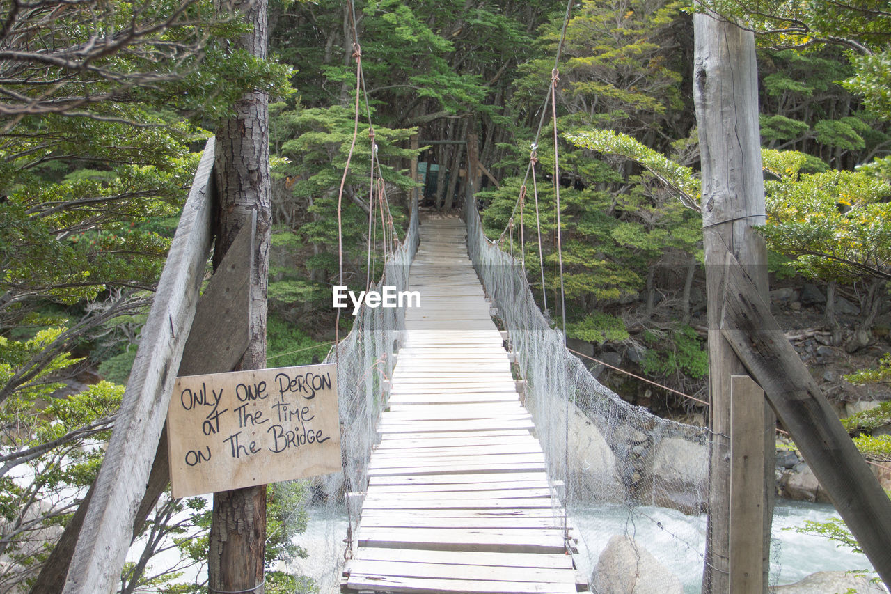 INFORMATION SIGN ON FOOTBRIDGE AMIDST TREES