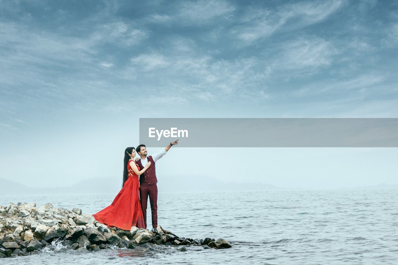 Woman standing by sea against sky