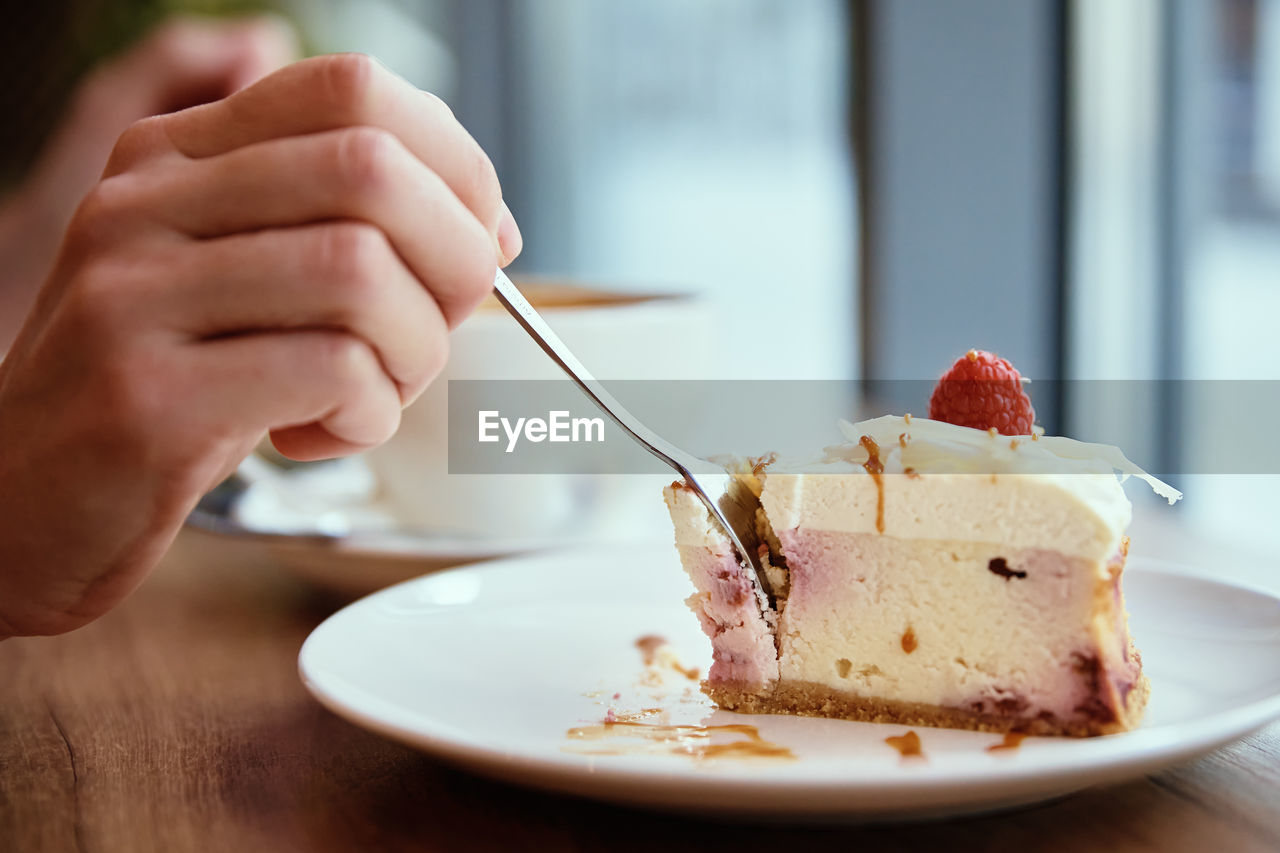 Woman have breakfast at cafe, eating raspberry cheesecake with coffee