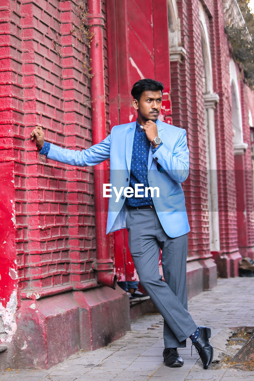 Full length of young man standing on sidewalk