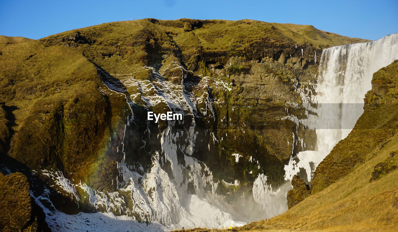 SCENIC VIEW OF WATERFALL AGAINST SKY