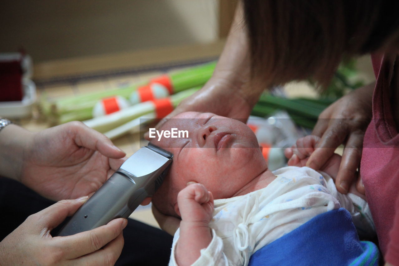 Man trimming baby hair through electric razor