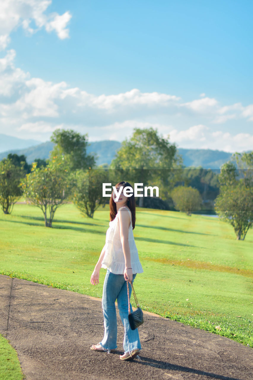 Rear view of woman walking on field against sky