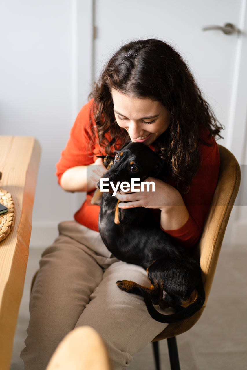 side view of young woman with dog sitting on sofa at home