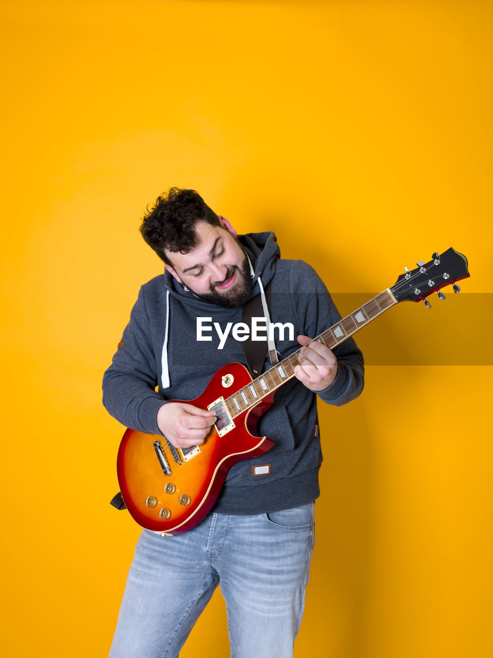 Man playing guitar against orange background