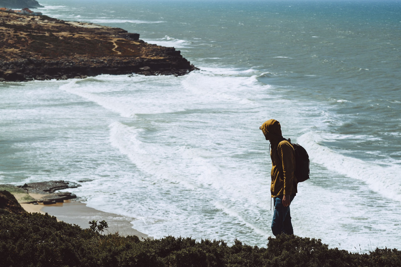 Side view of mid adult man standing at shore during sunny day