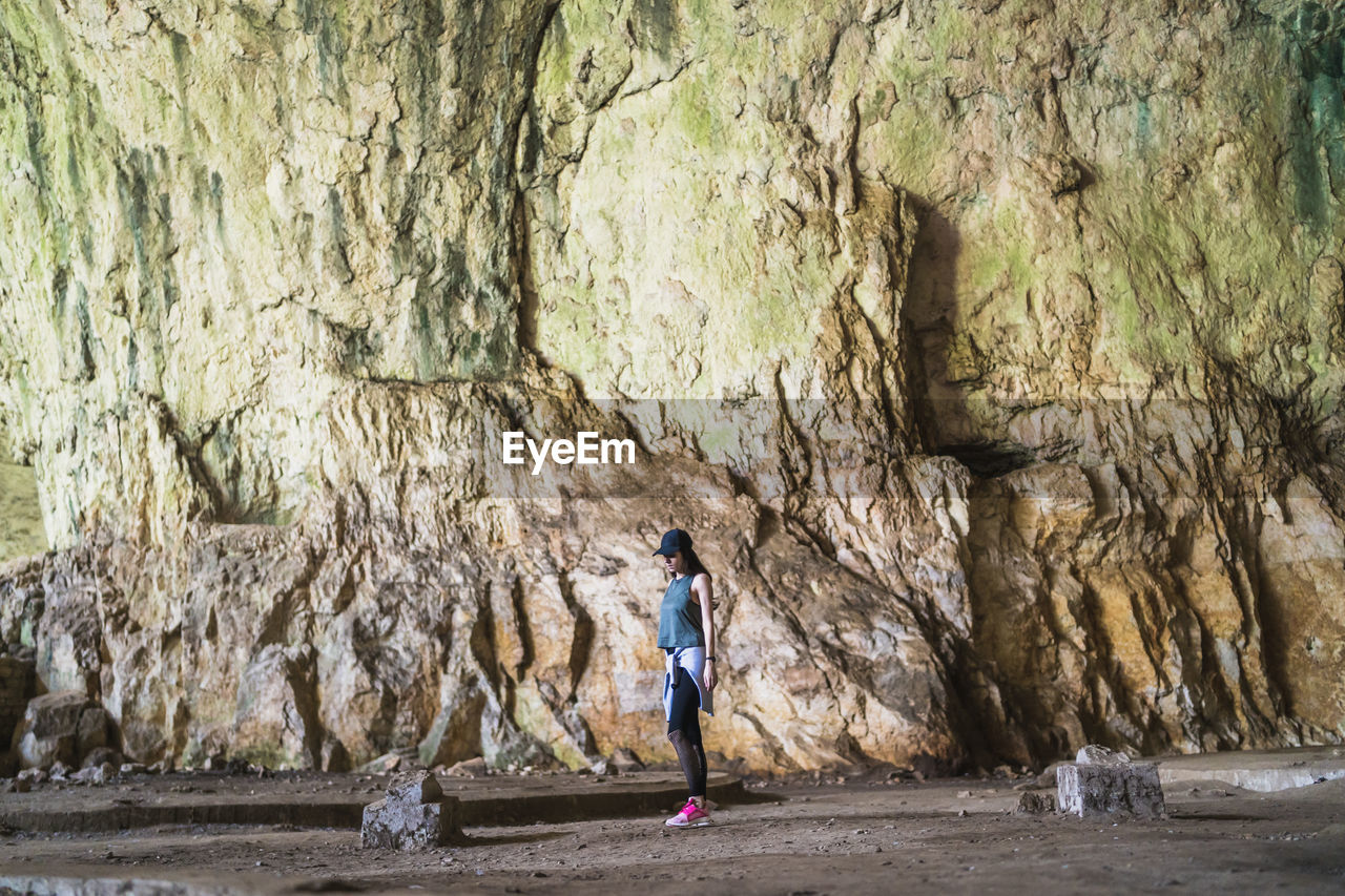 REAR VIEW OF WOMAN STANDING ON ROCK