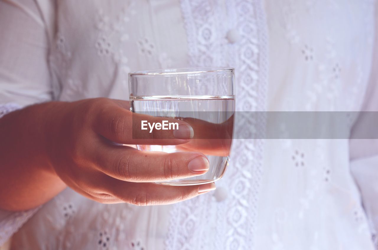 Midsection of woman holding drinking glass