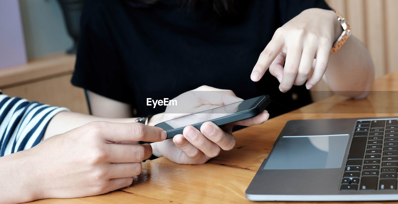 MIDSECTION OF WOMAN USING MOBILE PHONE