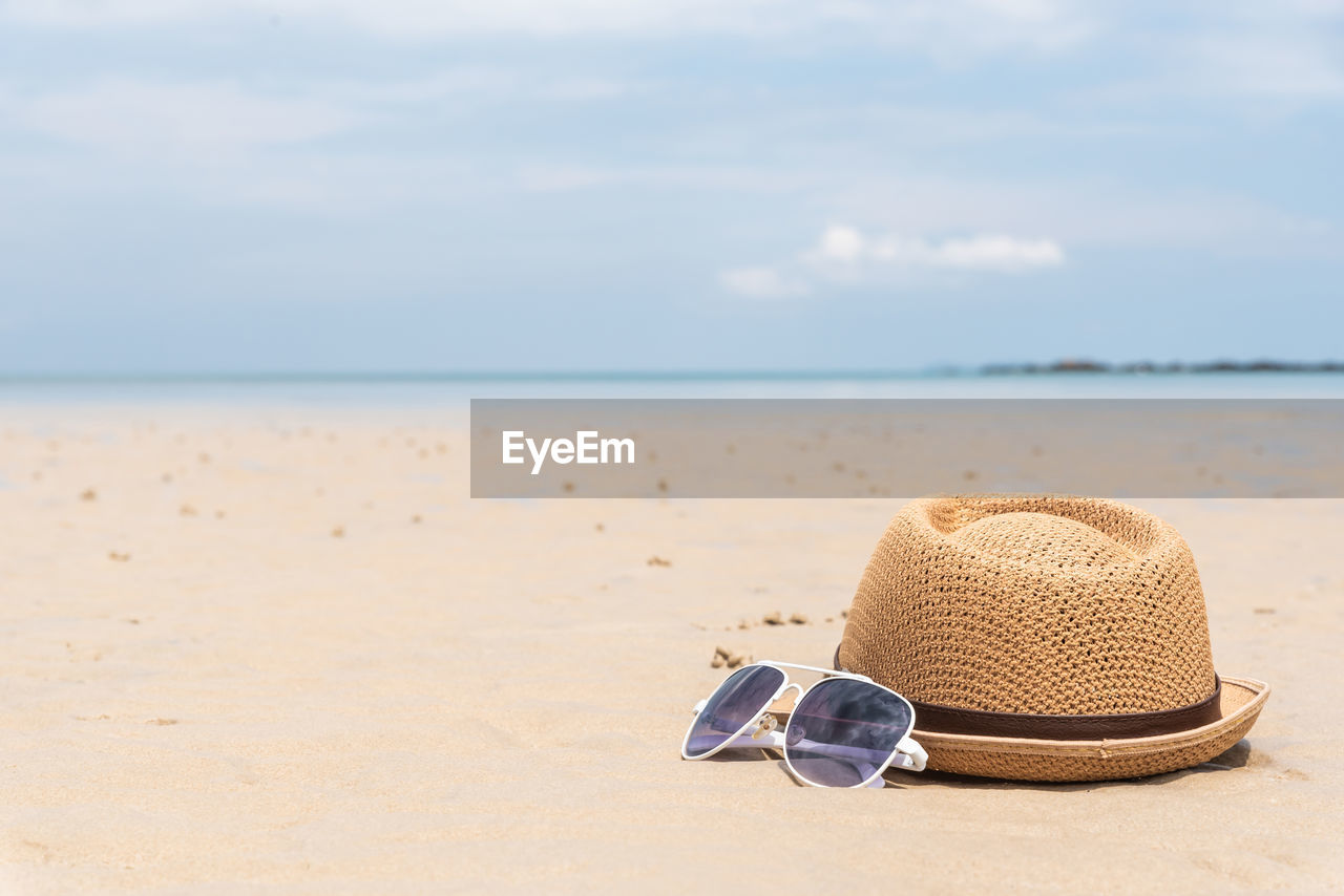 HAT ON BEACH AGAINST SKY