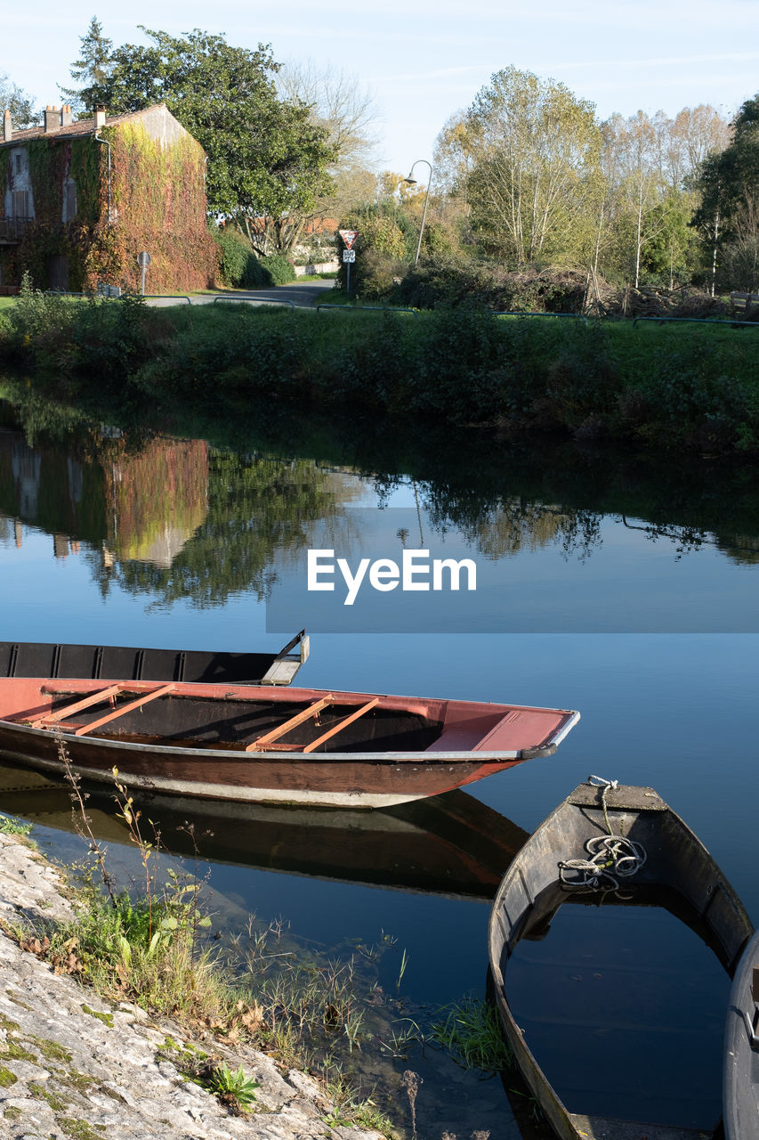 water, nautical vessel, lake, reflection, nature, transportation, boat, plant, tree, mode of transportation, vehicle, waterway, canoe, no people, moored, day, tranquility, boating, outdoors, sky, architecture, rowboat, watercraft, beauty in nature, travel, built structure