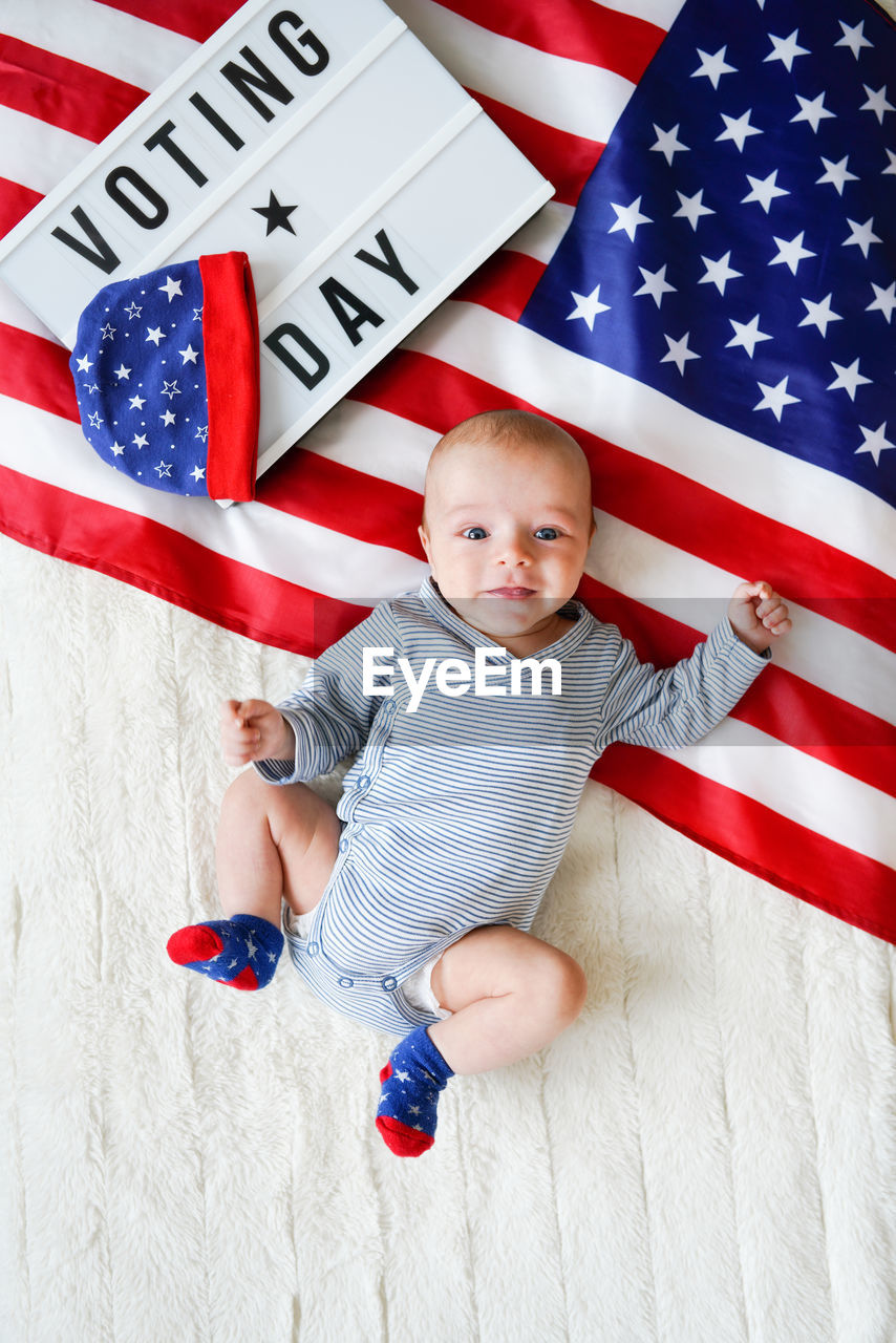 High angle view of cute baby lying on usa flag. voting day