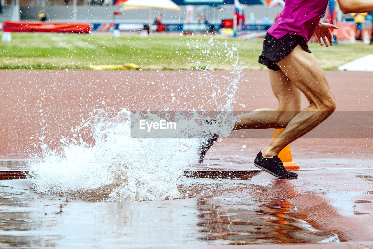 Steeplechase race legs male runner splashing water