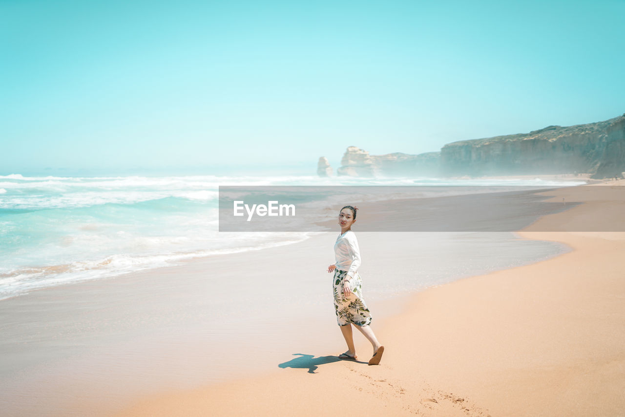 WOMAN ON BEACH AGAINST SKY