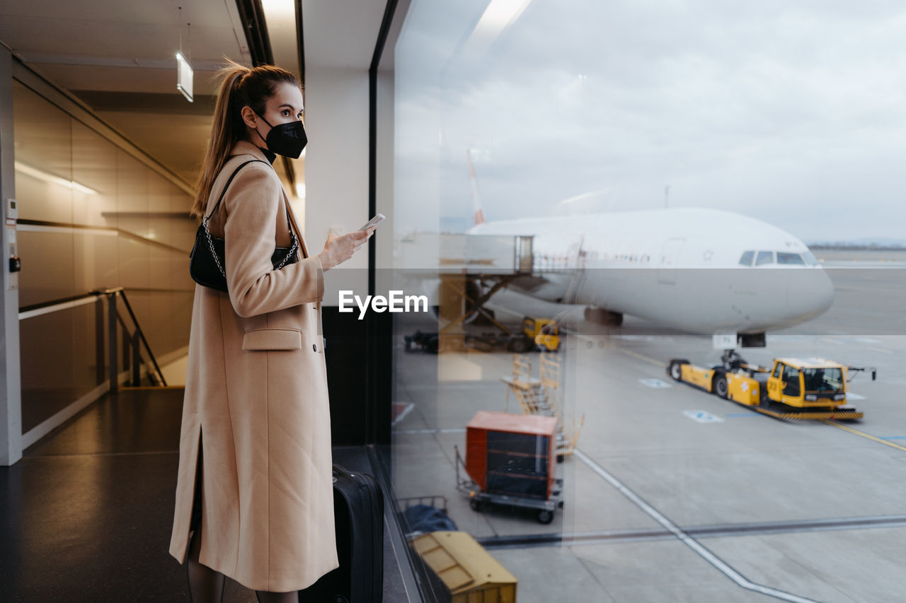 Side view of young woman standing at airport