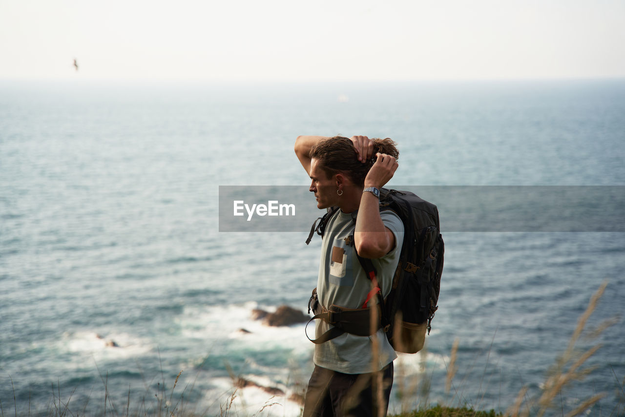 Male backpacker walking on hill during trekking in summer and looking away