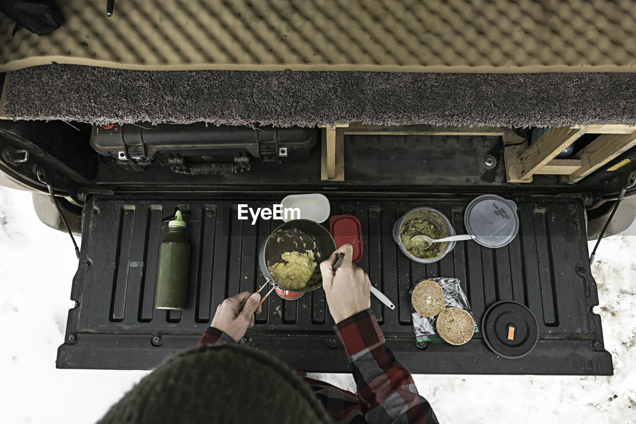 Overhead view of woman preparing food at trunk of off-road vehicle