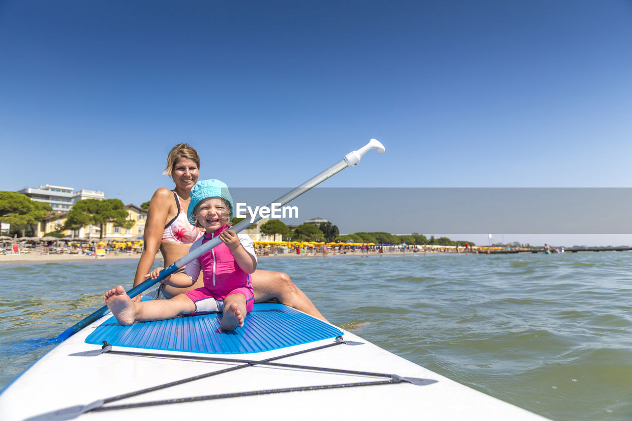 View  of happy woman and girl on paddleboard