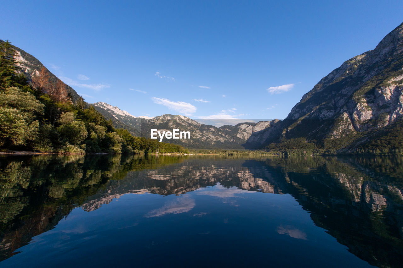 Scenic view of lake and mountains against blue sky