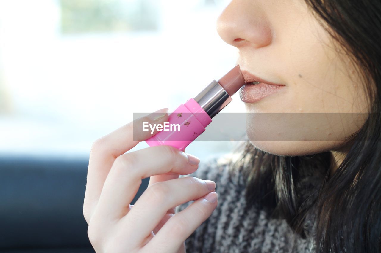 Close-up midsection of woman applying lipstick