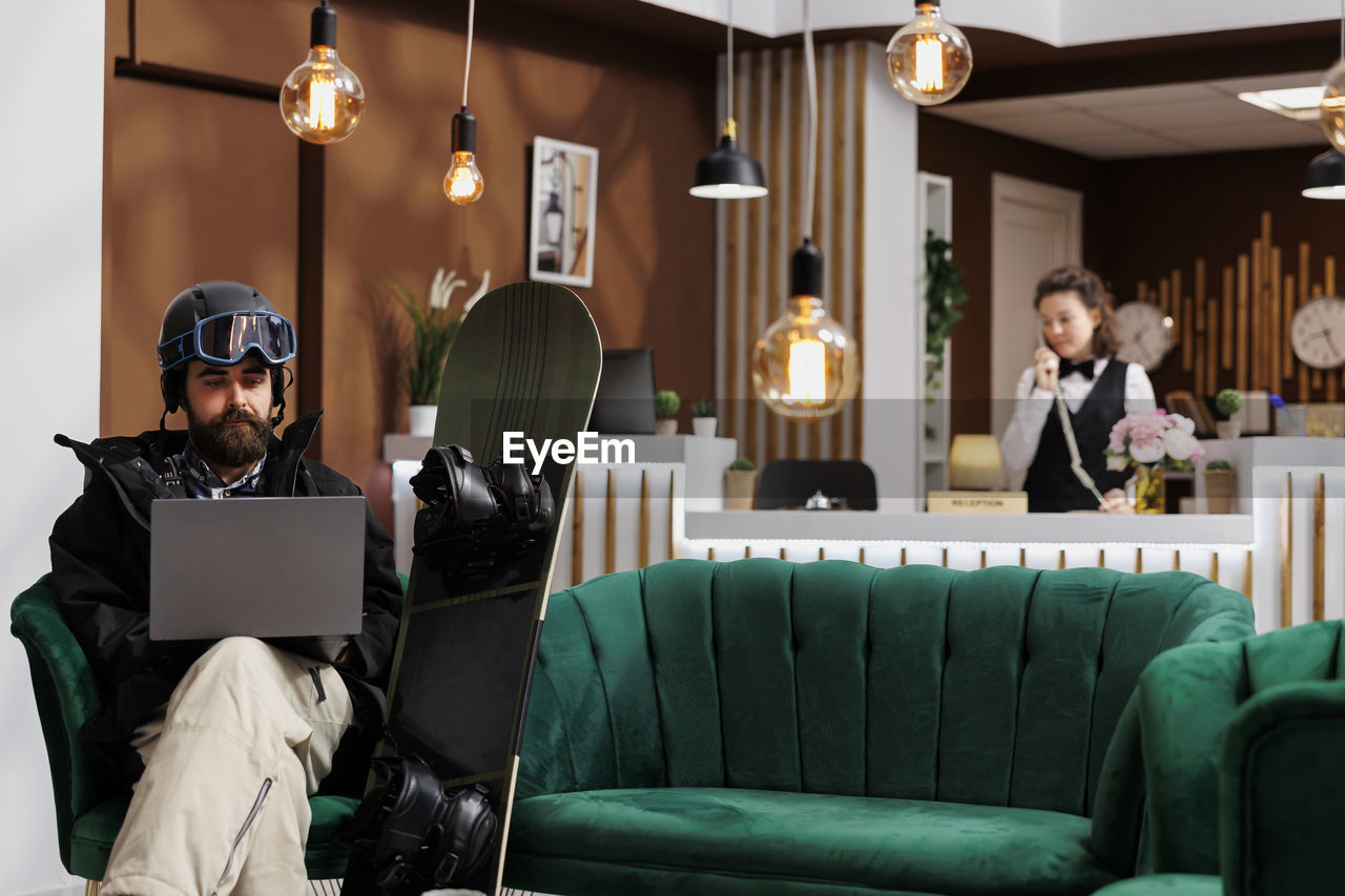 rear view of woman using laptop while sitting in restaurant