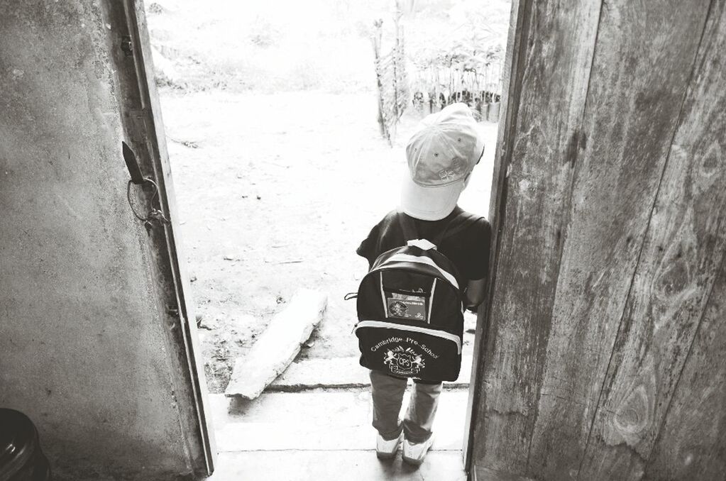 REAR VIEW OF BOY STANDING ON WALL