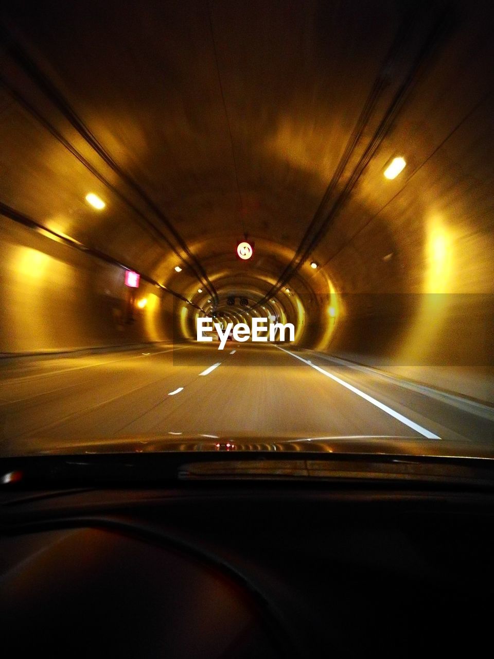 Illuminated tunnel seen through car windshield