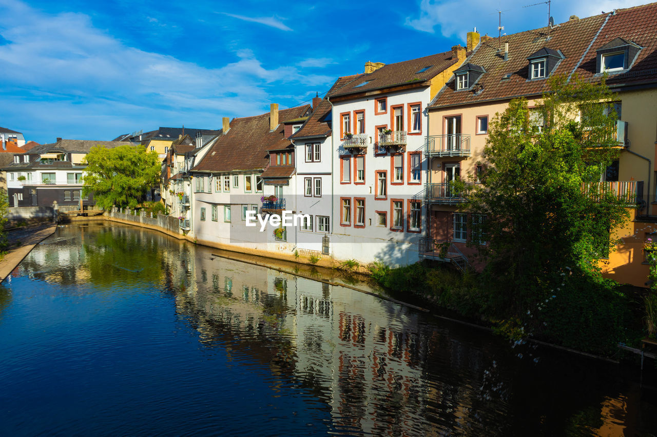 Houses by river in town against sky