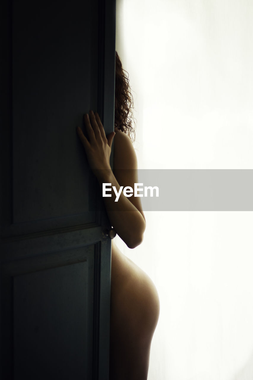 Naked woman standing at door