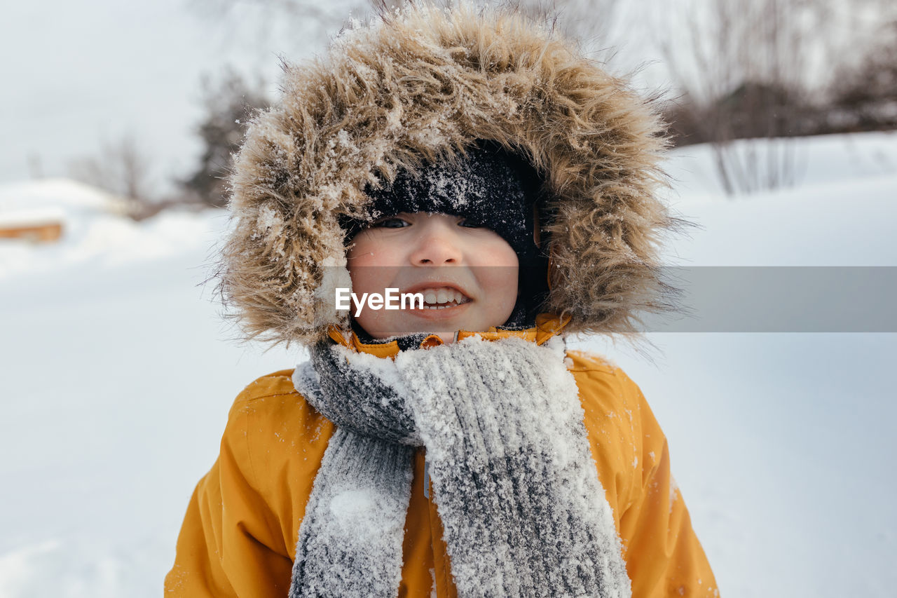 Close-up, image of a happy child in a hood in winter looking at the camera