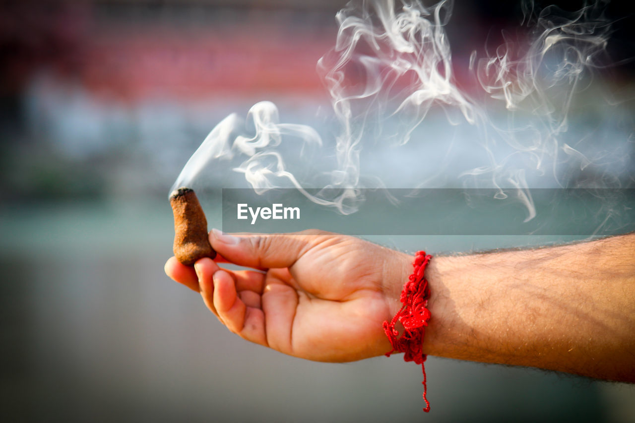 Cropped hand of man holding incense