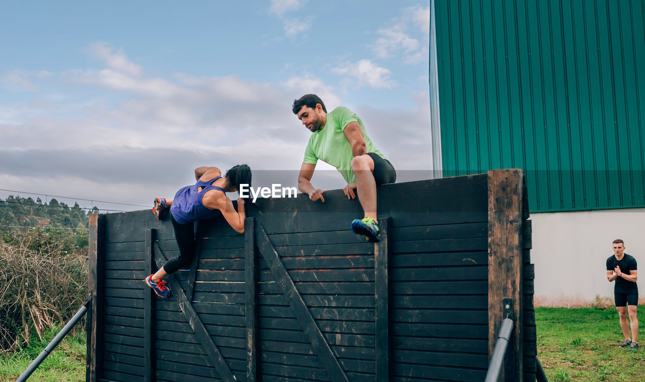 People climbing on wooden wall outdoors