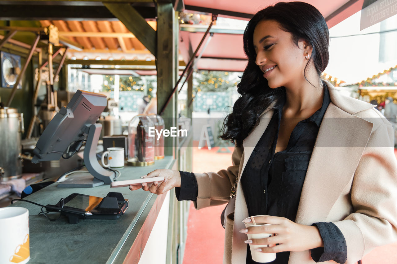 Woman paying through smart phone at food truck in market