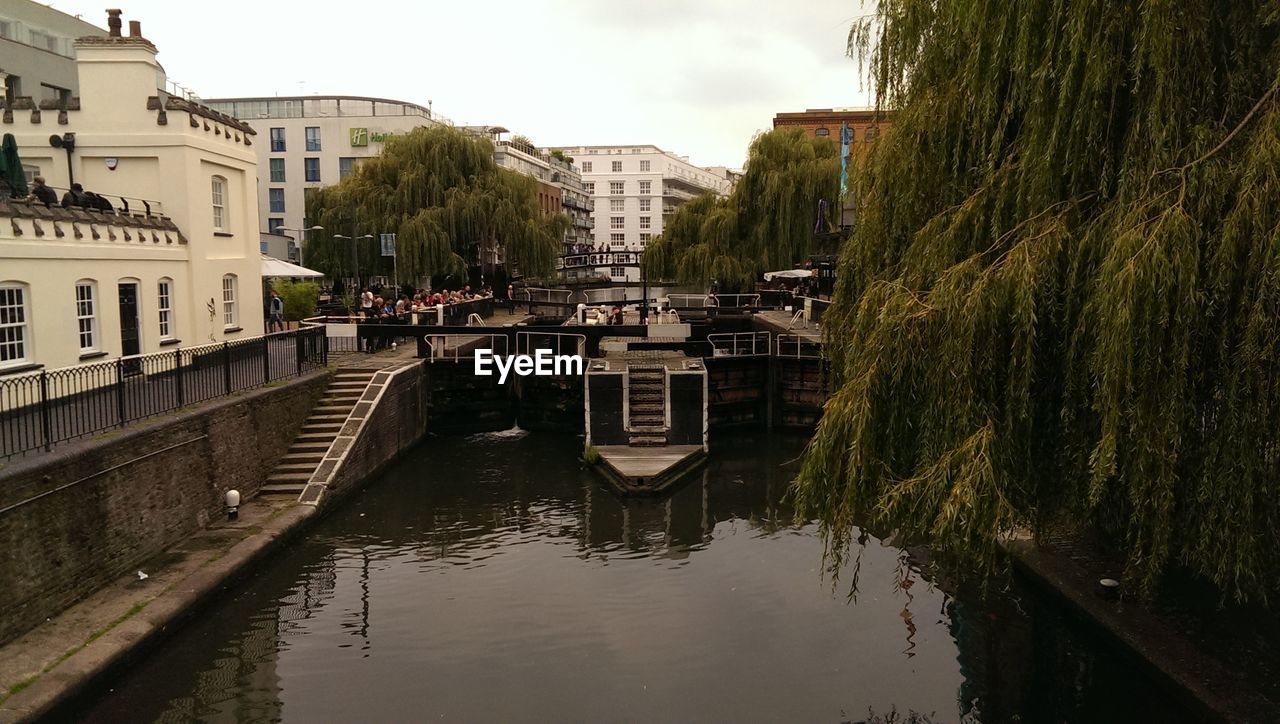 Canal in city against sky