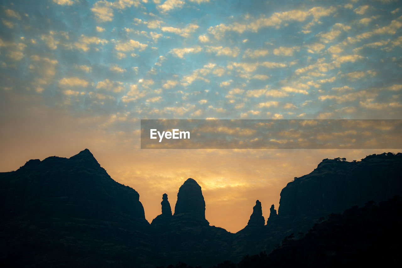 Silhouette rock formations against sky during sunset