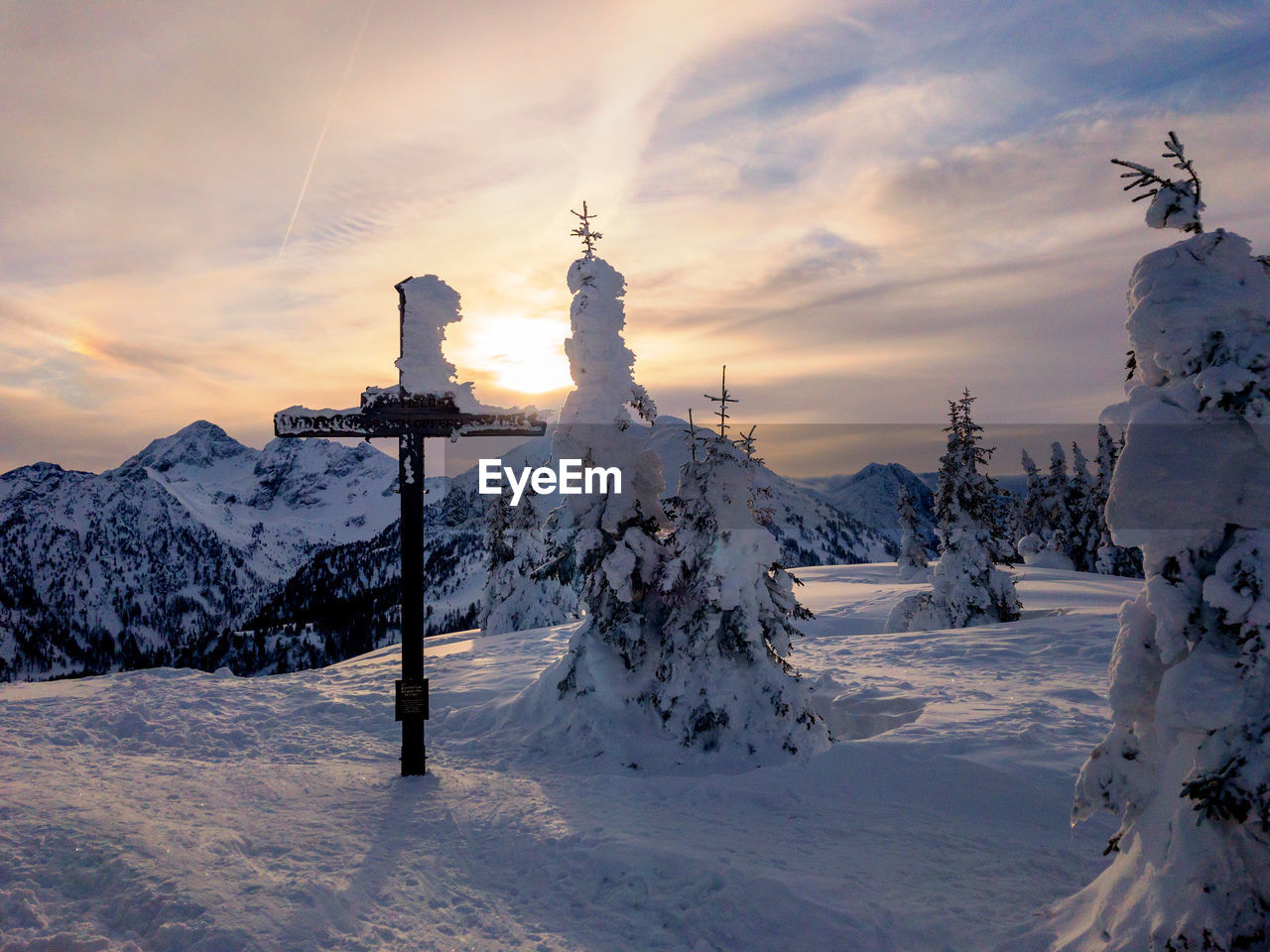 Snow covered land against sky during sunset