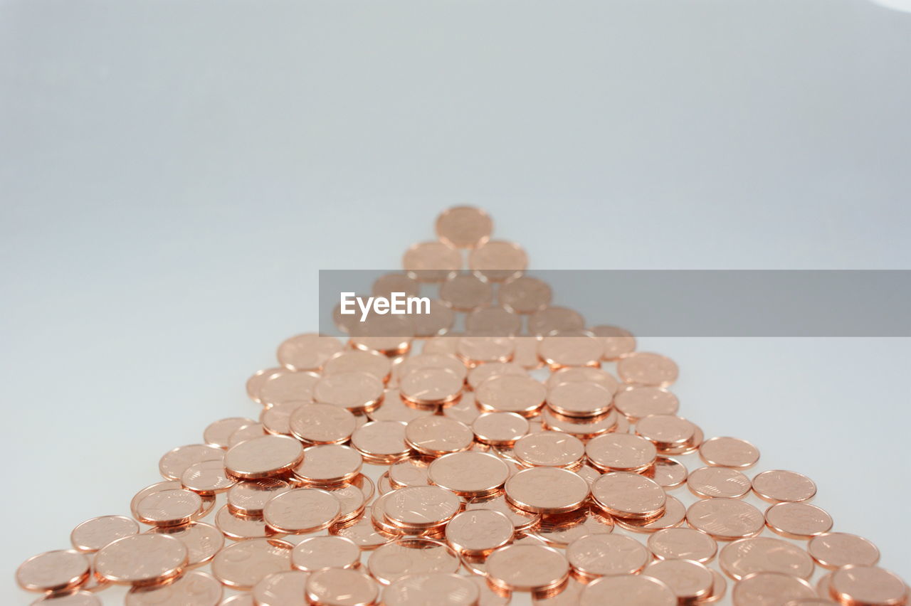 Close-up of coins arranged in triangle shape over white background