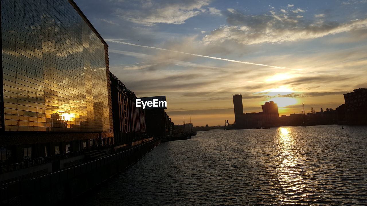 BRIDGE OVER RIVER BY BUILDINGS IN CITY AGAINST SKY