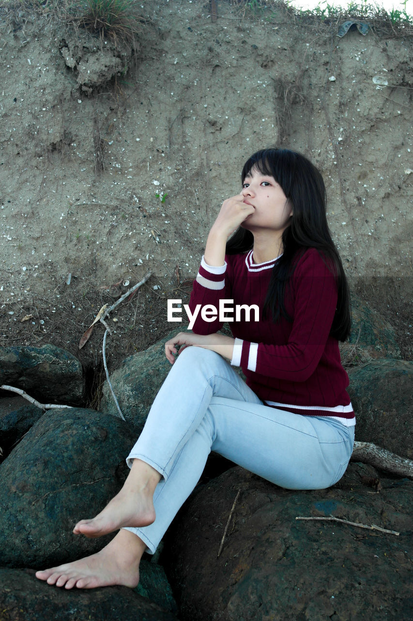 BEAUTIFUL WOMAN SITTING ON ROCK