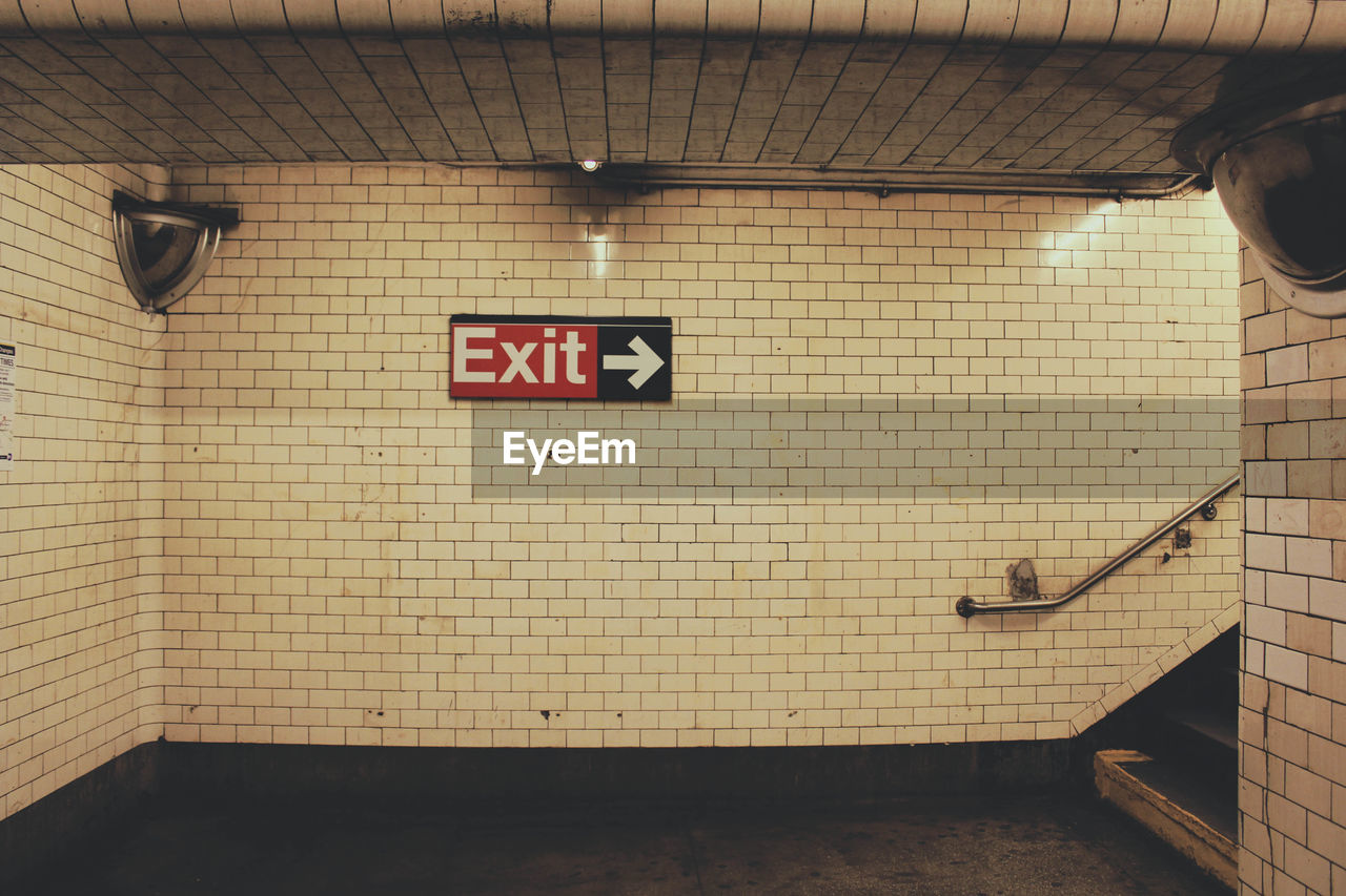 Exit sign on tile wall in subway station